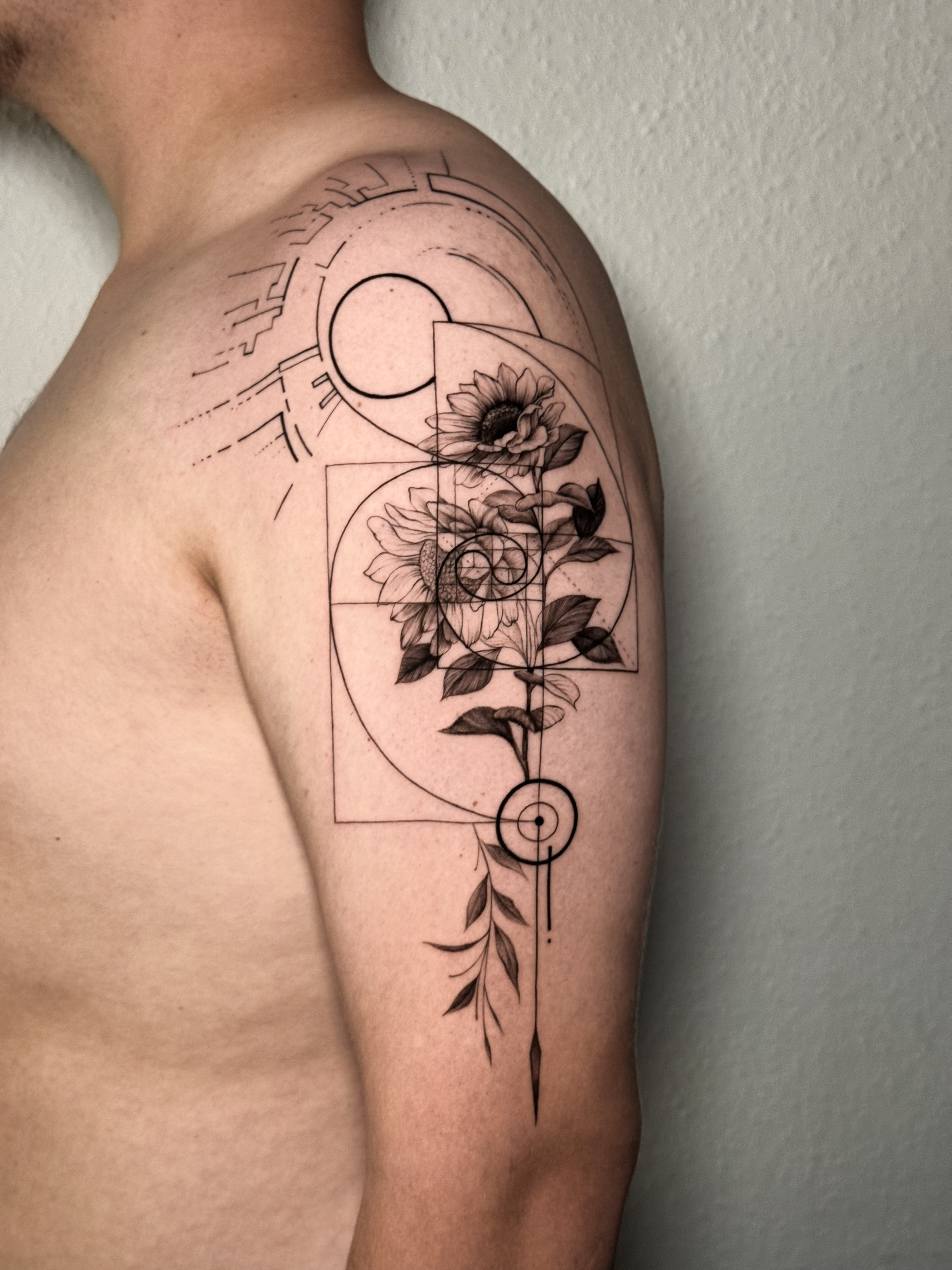 Concept-Tattoo mit Sonnenblumen, geometrischen Linien und Kreisen auf dem Oberarm.